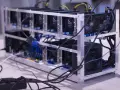 Rząd kart graficznych w aluminiowej ramie, podłączonych kablami. To serce kopalni kryptowalut, pracujące na pełnych obrotach.