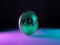 Błyszczący, zielony bitcoin na tle fioletowo-niebieskiego światła. Symbolizuje przyszłość finansów i potencjalny wzrost wartości bit usd.