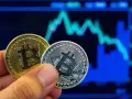 Złoty i srebrny bitcoin w dłoni na tle wykresu giełdowego. Symbolizuje to bitcoin revolution i przyszłość finansów.