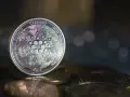 Moneta Cardano (ADA) na stosie innych monet. W tle rozmyte światła, sugerujące analizę i prognozy dotyczące przyszłości kryptowaluty.