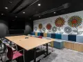 Nowoczesny trading room z dużym stołem, krzesłami i kolorową ścianą z motywem słoneczników.