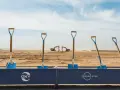 Symboliczne łopaty na placu budowy, gdzie Occidental Petroleum (OXY) rozpoczyna nowy projekt. W tle koparki i wieża.