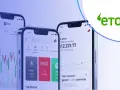 Trzy smartfony prezentujące aplikację eToro z wykresami giełdowymi i informacjami o inwestycjach. Sprawdź eToro opłaty przed rozpoczęciem handlu.
