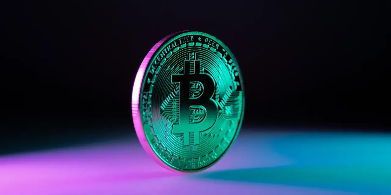Błyszczący, zielony bitcoin na tle fioletowo-niebieskiego światła. Symbolizuje przyszłość finansów i potencjalny wzrost wartości bit usd.