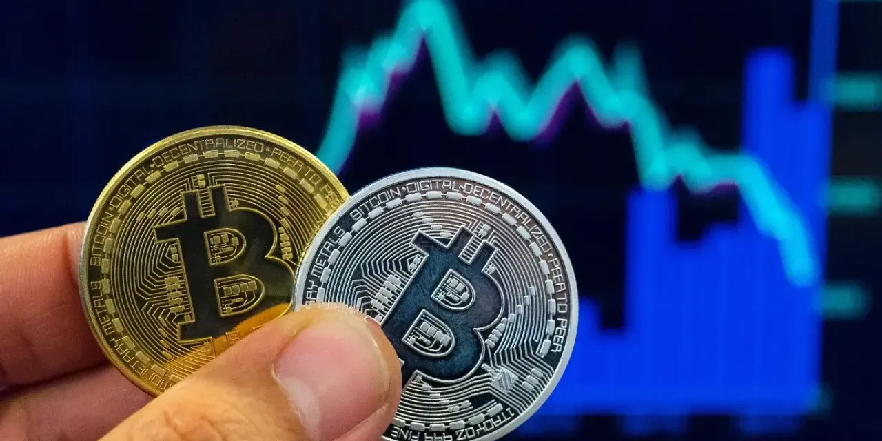 Złoty i srebrny bitcoin w dłoni na tle wykresu giełdowego. Symbolizuje to bitcoin revolution i przyszłość finansów.