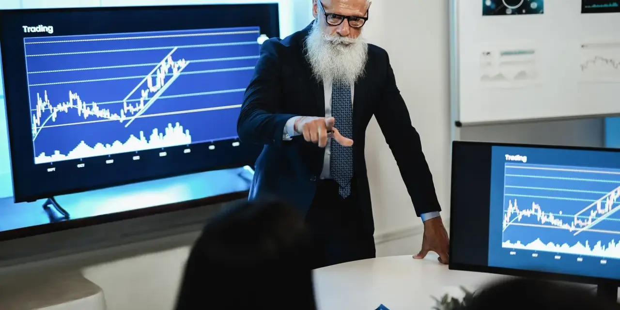 Starszy mężczyzna z brodą analizuje wykresy, omawiając strategię inwestycyjną. Sony akcje rosną!