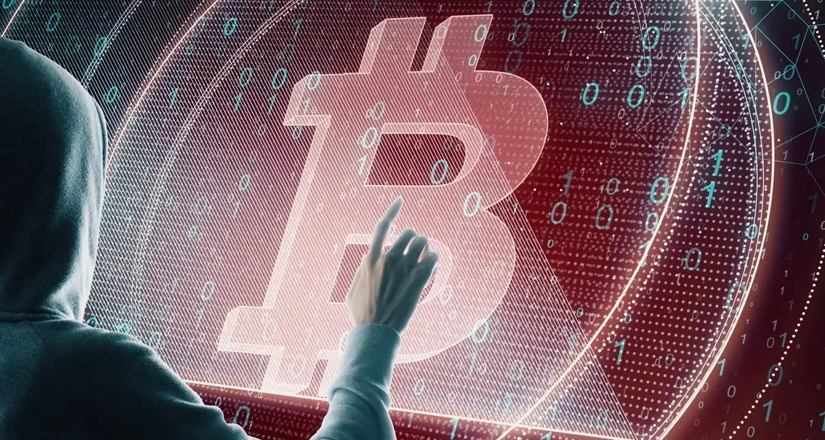 Osoba w kapturze dotyka symbolu Bitcoina na tle kodu binarnego. Czy to ślad po majątku Satoshi Nakamoto?