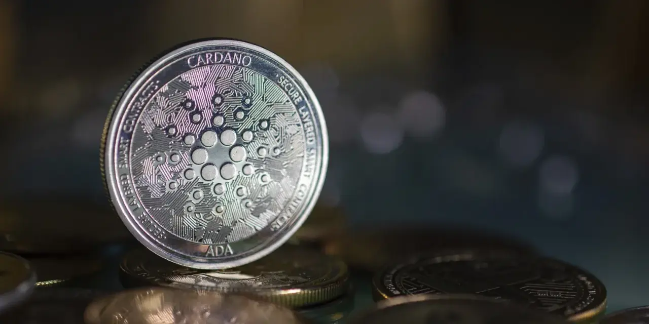 Moneta Cardano (ADA) na stosie innych monet. W tle rozmyte światła, sugerujące analizę i prognozy dotyczące przyszłości kryptowaluty.
