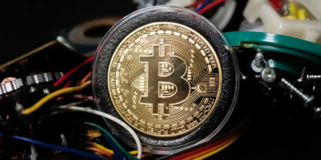Złoty Bitcoin w otoczeniu kabli i elektroniki, symbolizujący darmowe kopanie kryptowalut.