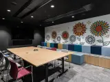 Nowoczesny trading room z dużym stołem, krzesłami i kolorową ścianą z motywem słoneczników.