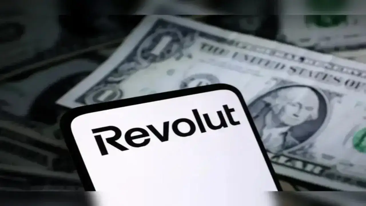 Telefon z logo Revolut na tle banknot&oacute;w dolarowych. Czy to zapowiedź przyszłego revolut IPO?