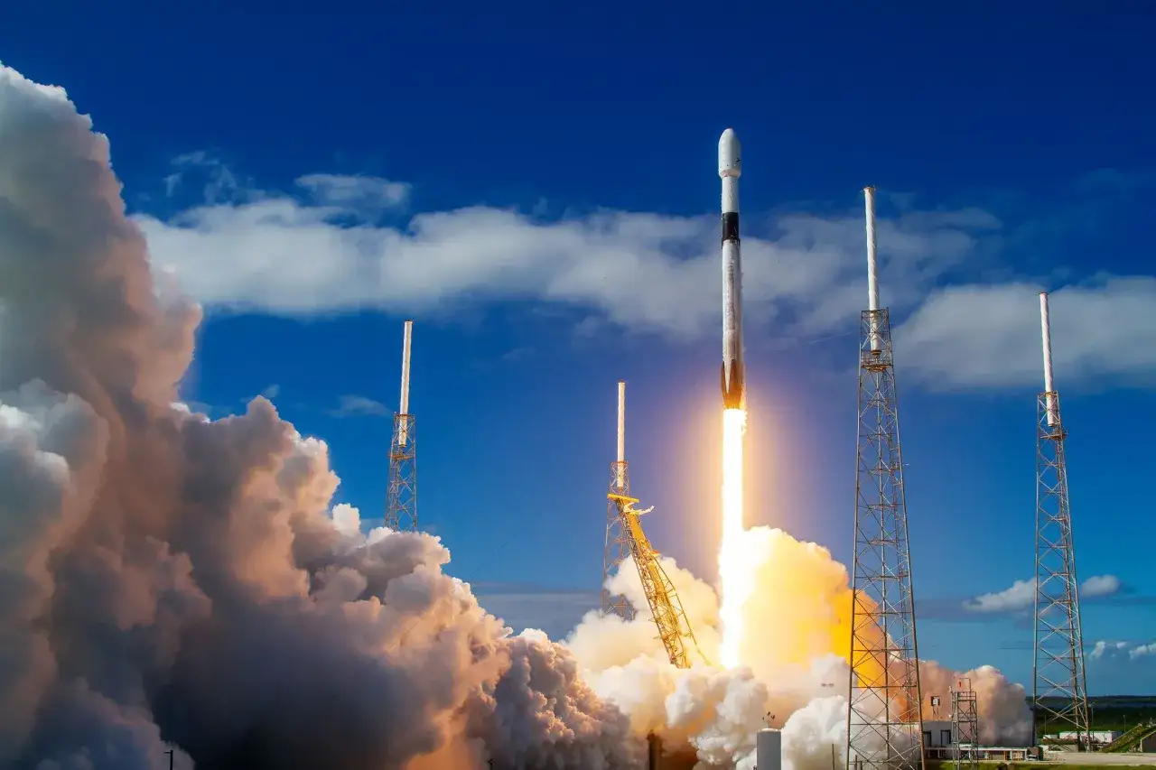 Rakieta Starlink startuje, wzbijając się w niebo z chmurami dymu. To symbol postępu i przyszłości, a jej akcje mogą przynieść zyski.